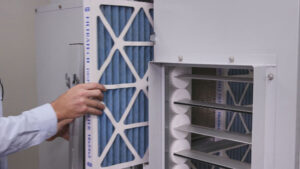 Technician replacing a pleated air filter in a commercial air handling unit during scheduled maintenance