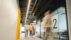 Modern commercial office corridor with exposed ceiling ductwork and glass meeting rooms